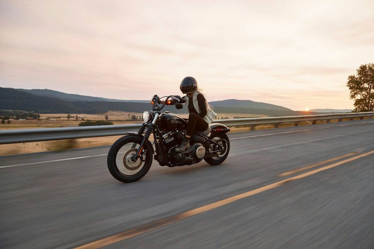 A rider on a cruiser motorcycle on an open road at sunset