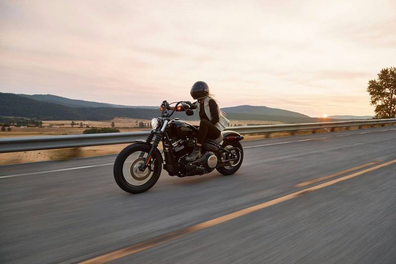 A rider on a cruiser motorcycle on an open road at sunset