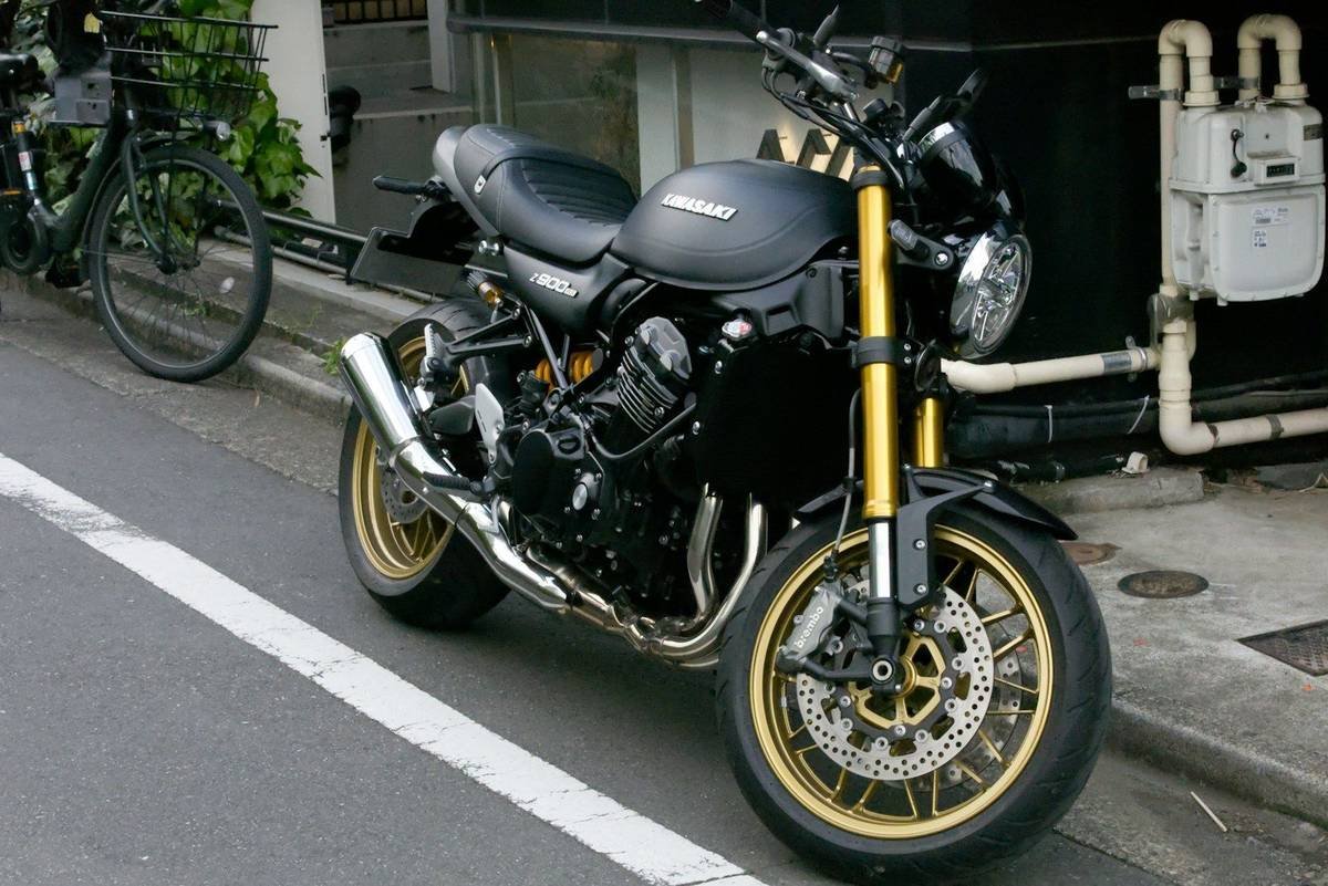 A black Kawasaki motorcycle with gold forks parked on a street in Japan