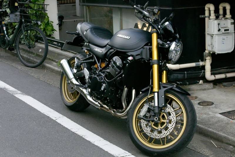 A black Kawasaki motorcycle with gold forks parked on a street in Japan
