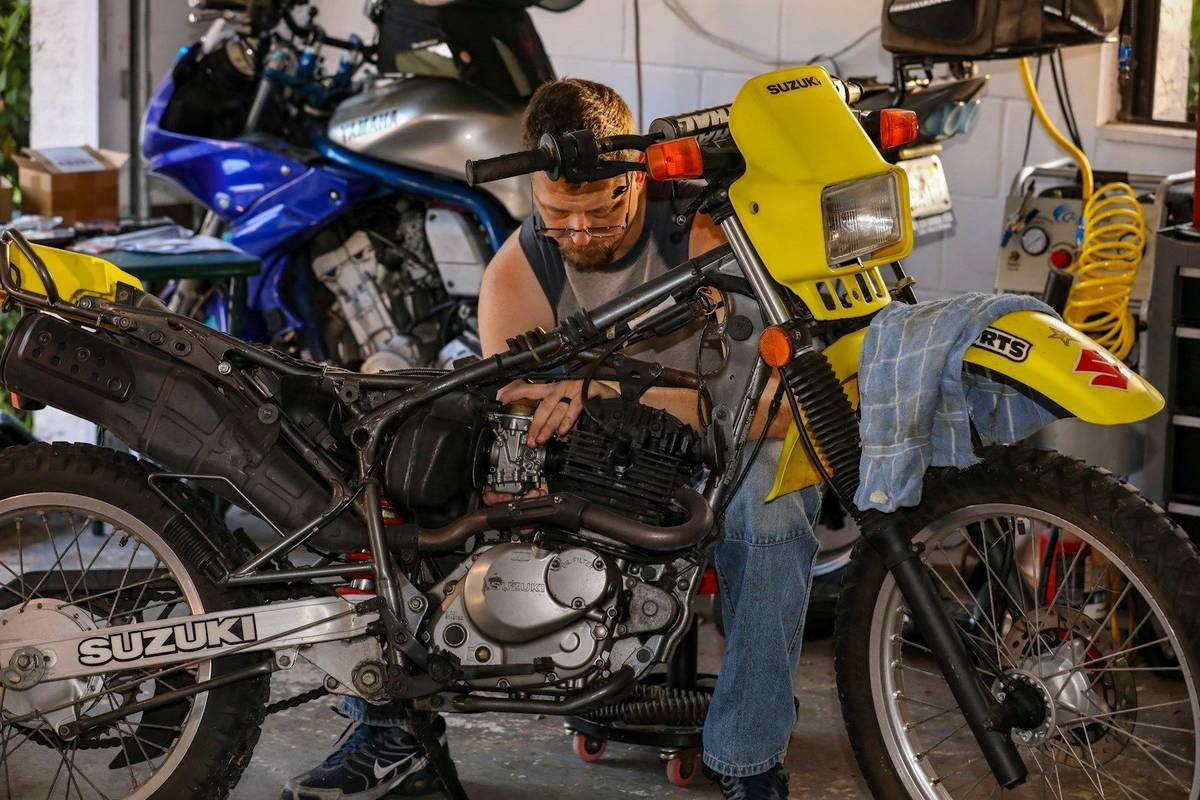 A mechanic working on the engine of a motorcycle in a garage