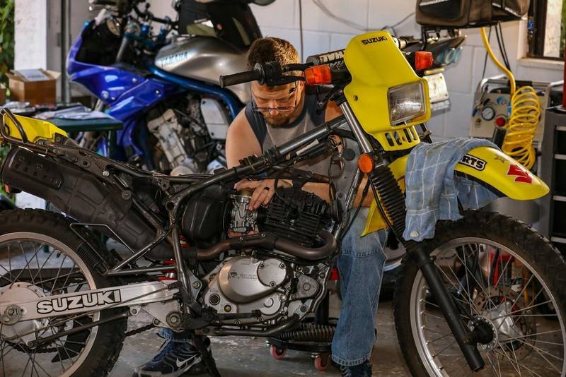 A mechanic working on the engine of a motorcycle in a garage