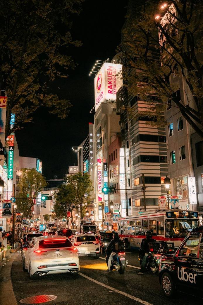 A busy city street at night with traffic and neon signs