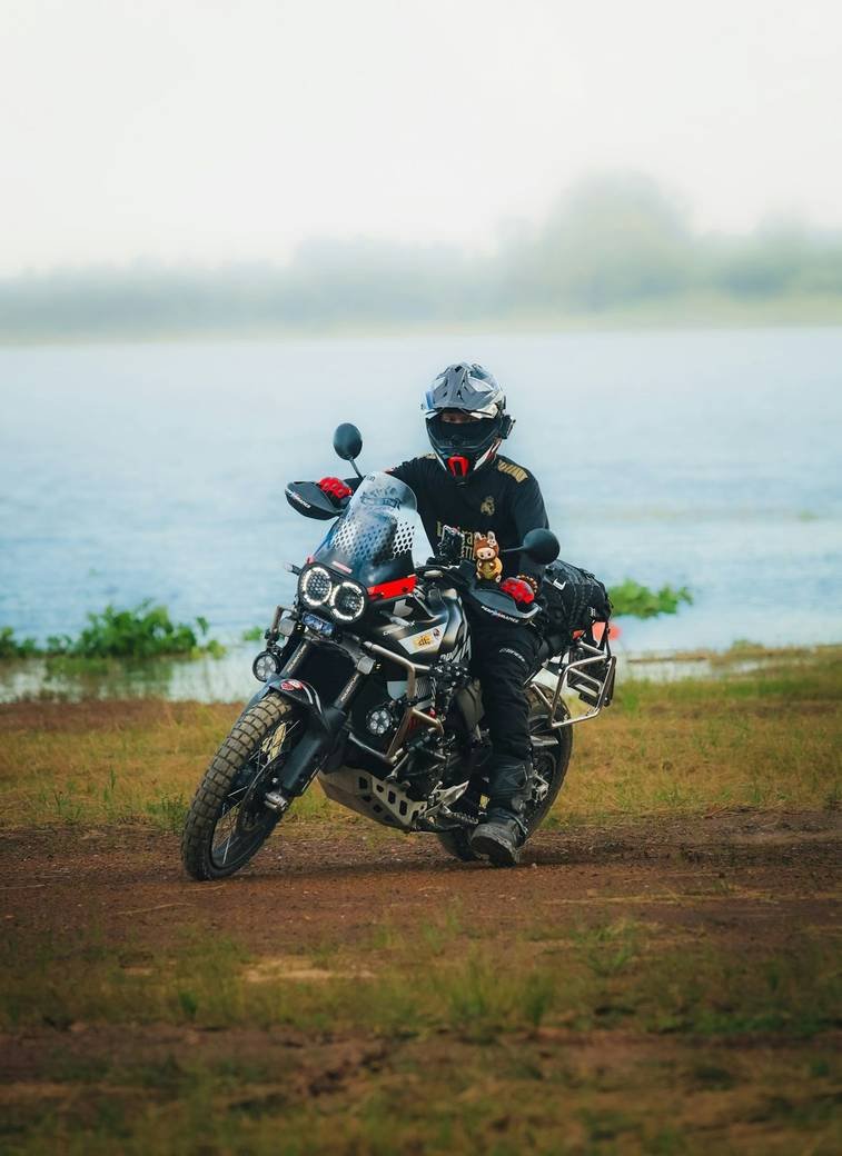 A rider on an adventure motorcycle by a lake