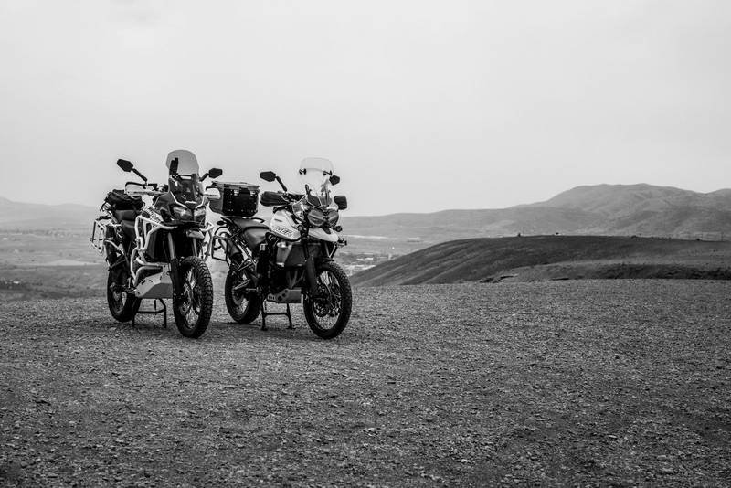 Two touring motorcycles parked on open ground, in black and white