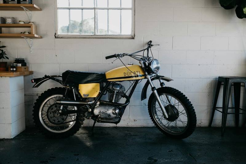 A vintage yellow motorcycle parked in a white garage